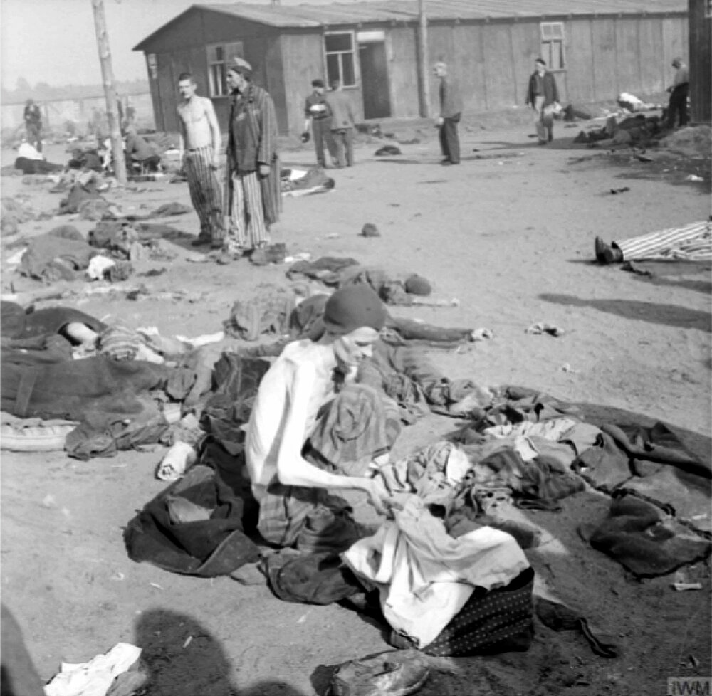 An unknown inmate among corpses in the liberated Bergen-Belsen concentration camp.